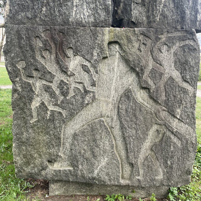 Picture of one side of the memorial sculpture in honor of Kristan Raud in Tallinn's Hirve Park (deer park) by sculptor Kalju Reitel and architect Eha Reitel, showing scenes from the Kalevipoeg poem.